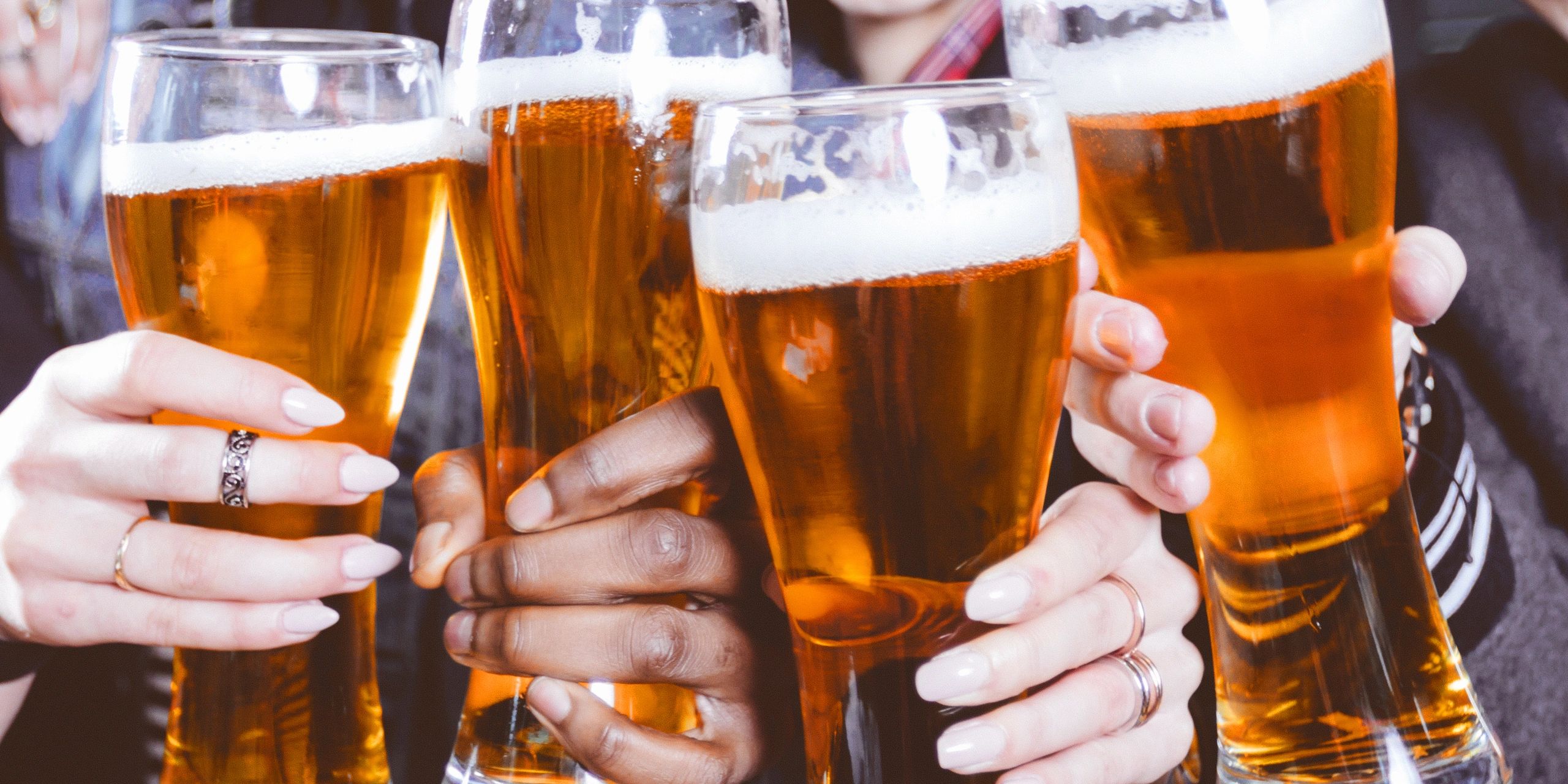 Cropped banner of friends toasting with beer glasses at the bar